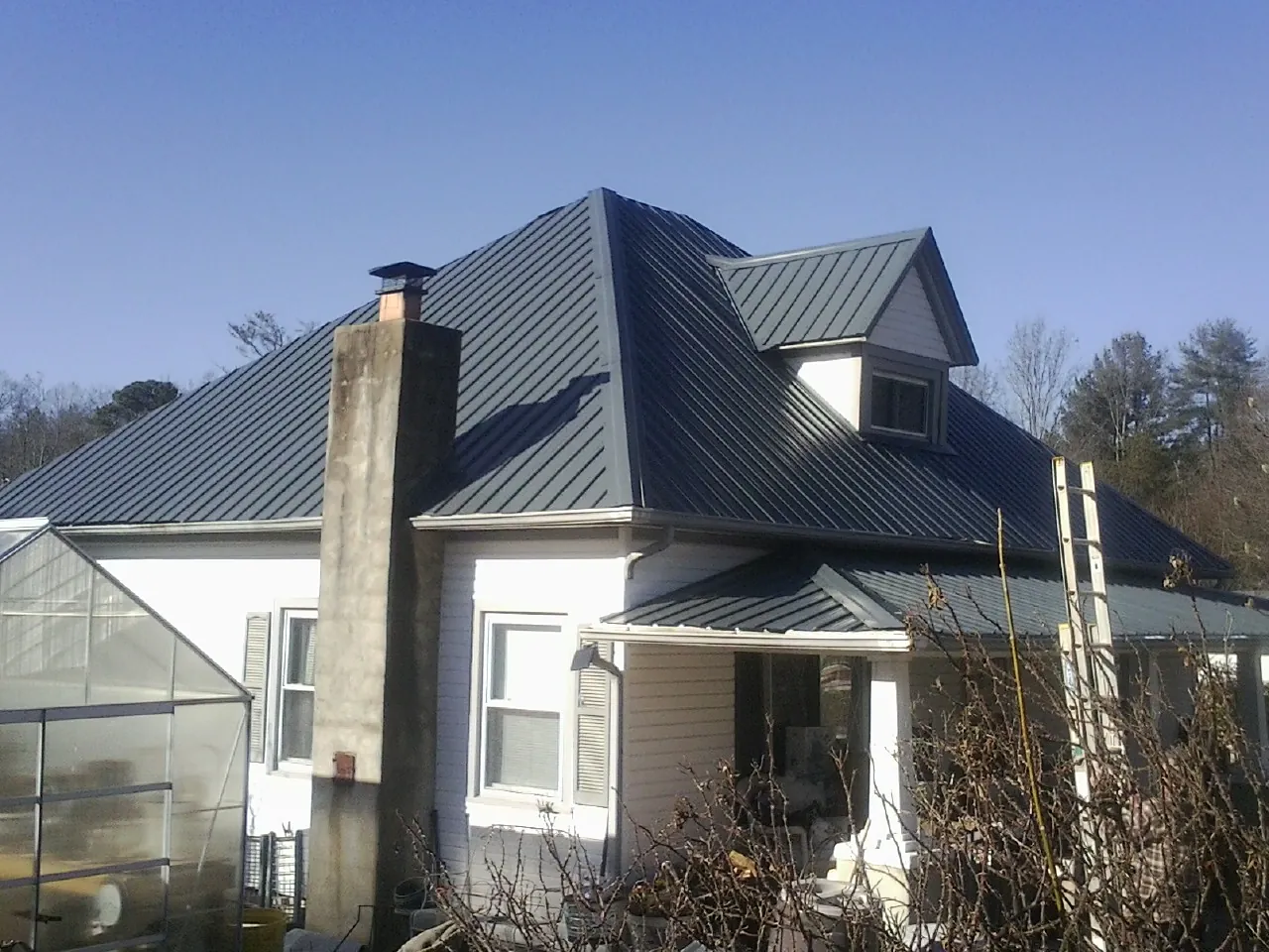 Dark blue standing seam metal roof on a white farmhouse with dormer — Slate & Tile Roof Repair by Roofing Brothers in Wilton